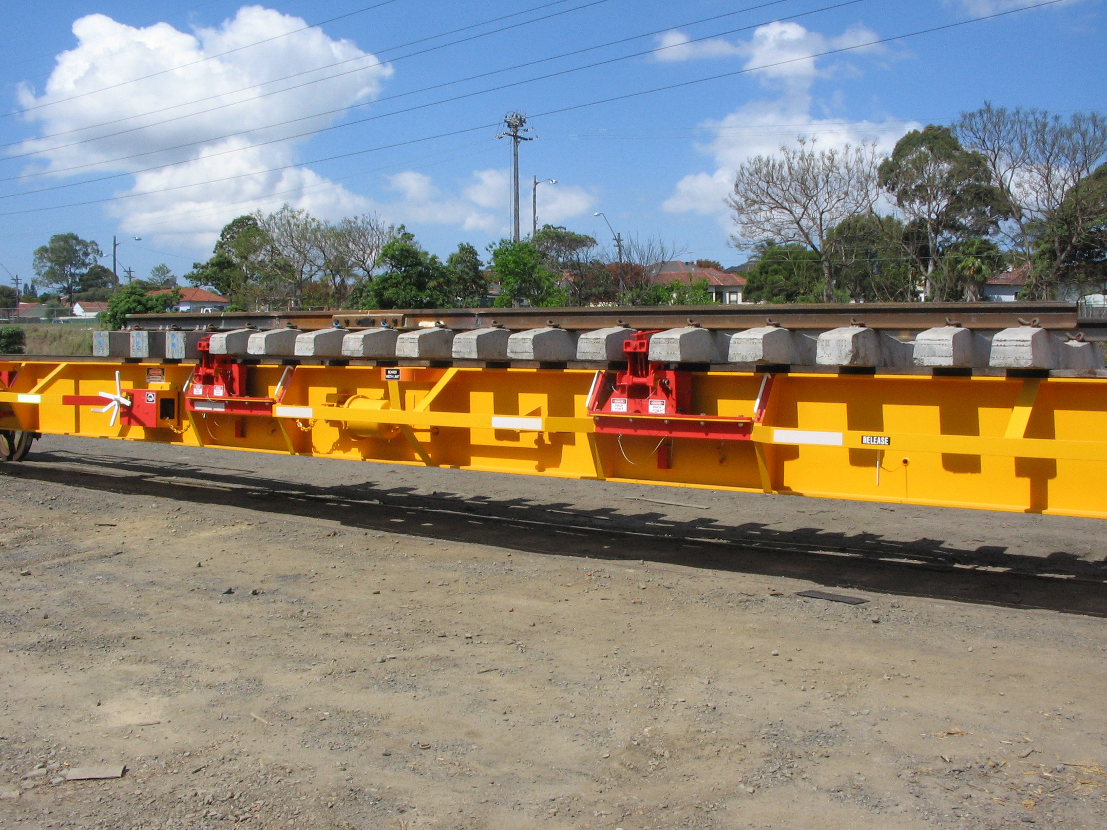 Long yellow rail wagon loaded with a turnout under a blue sky